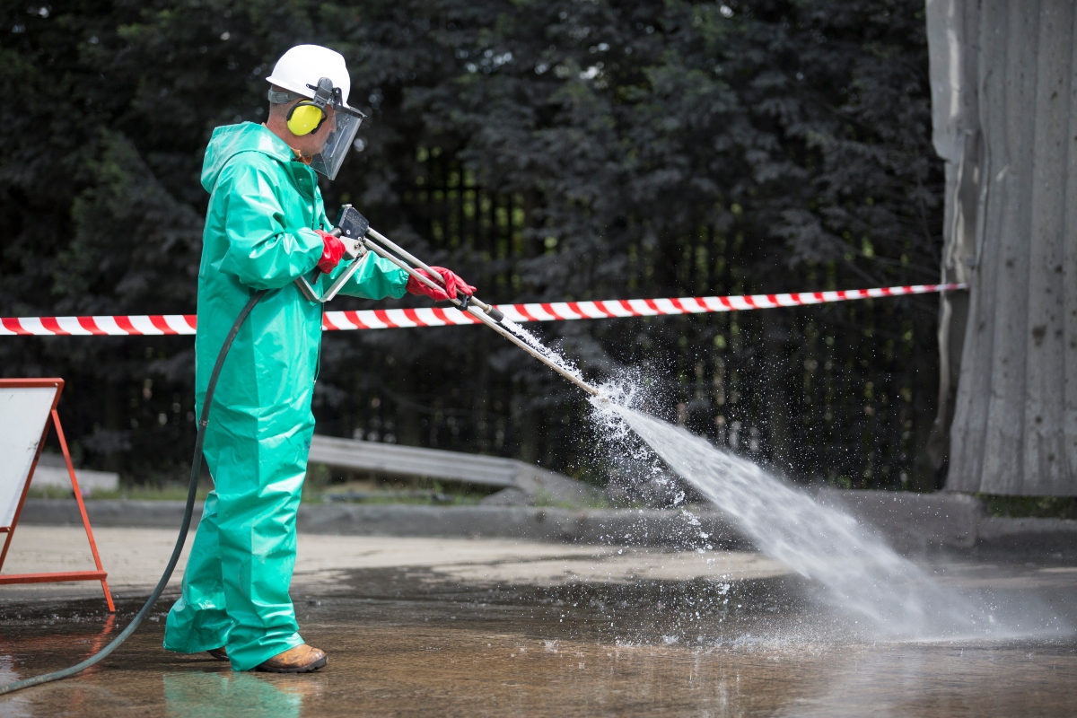 CSG Employee in full PPE with a High-Pressure jetter cleaning asphalt on an industrial plant.